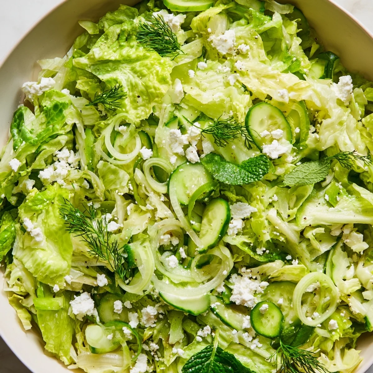 Fresh Greek maroulosalata salad with shredded romaine, herbs, and bright lemon dressing in a white bowl