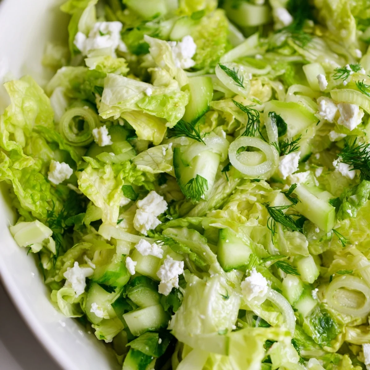 Rustic bowl of traditional Greek maroulosalata dressed with lemon juice and topped with crumbled feta cheese