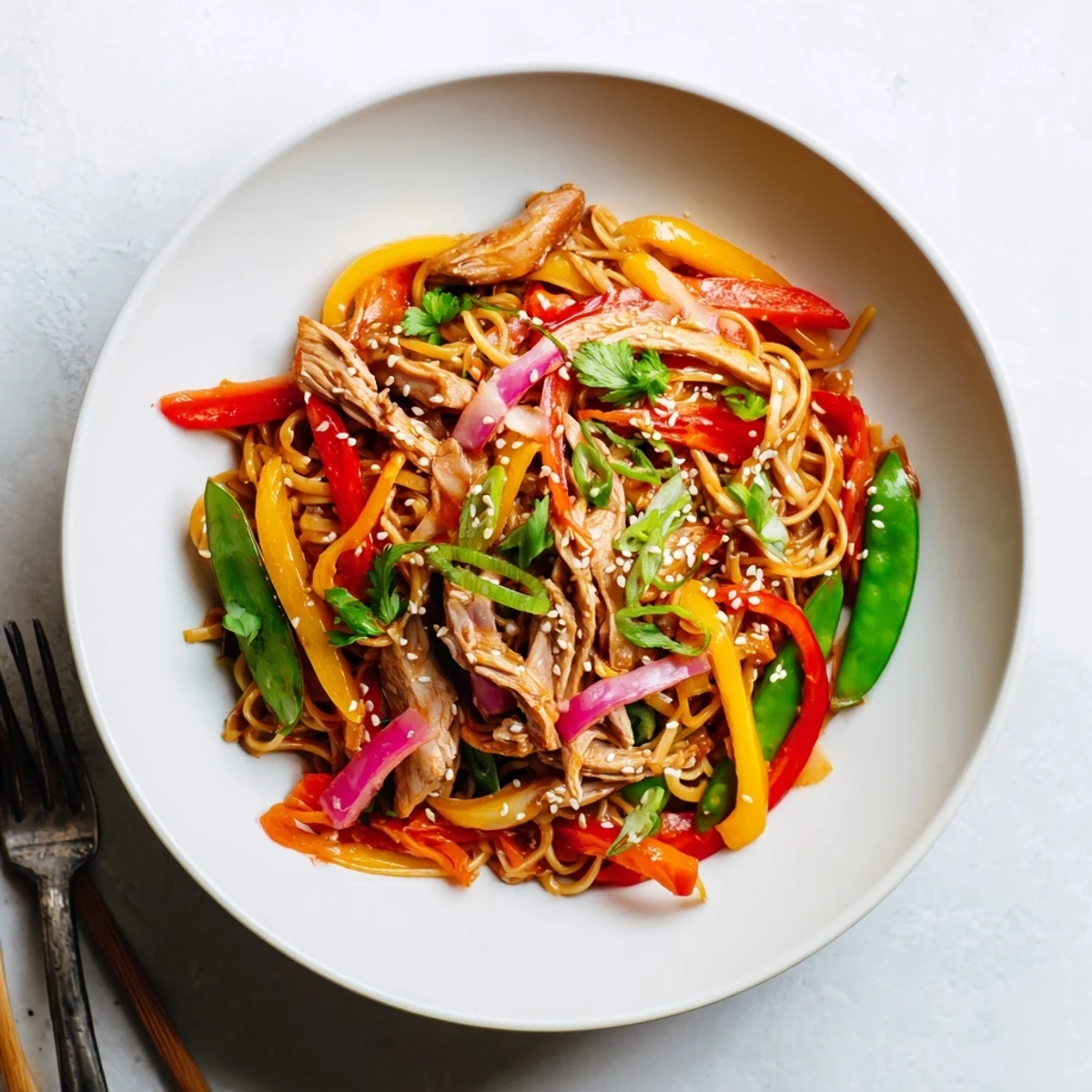 Steaming bowl of sweet chilli turkey noodle stir fry loaded with colorful peppers and snap peas