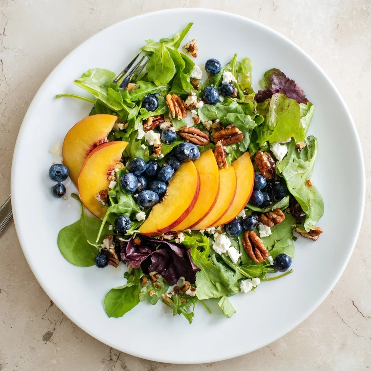 Fresh blueberry peach feta salad with juicy ripe peaches and creamy crumbled feta on mixed greens drizzled with light balsamic dressing