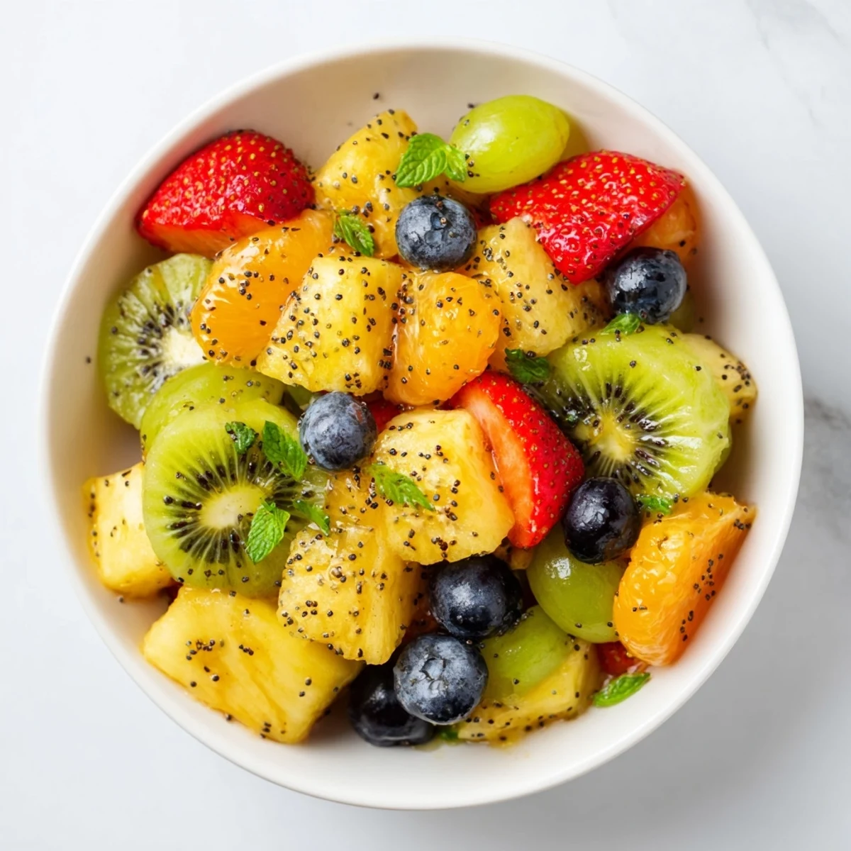 Festive Easter fruit salad arranged on white plate with honey lime drizzle and fresh mint