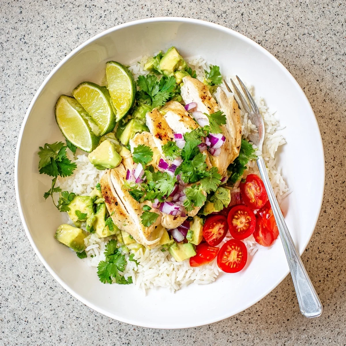 Sliced honey lime chicken resting atop fluffy rice and creamy avocado in a layered serving