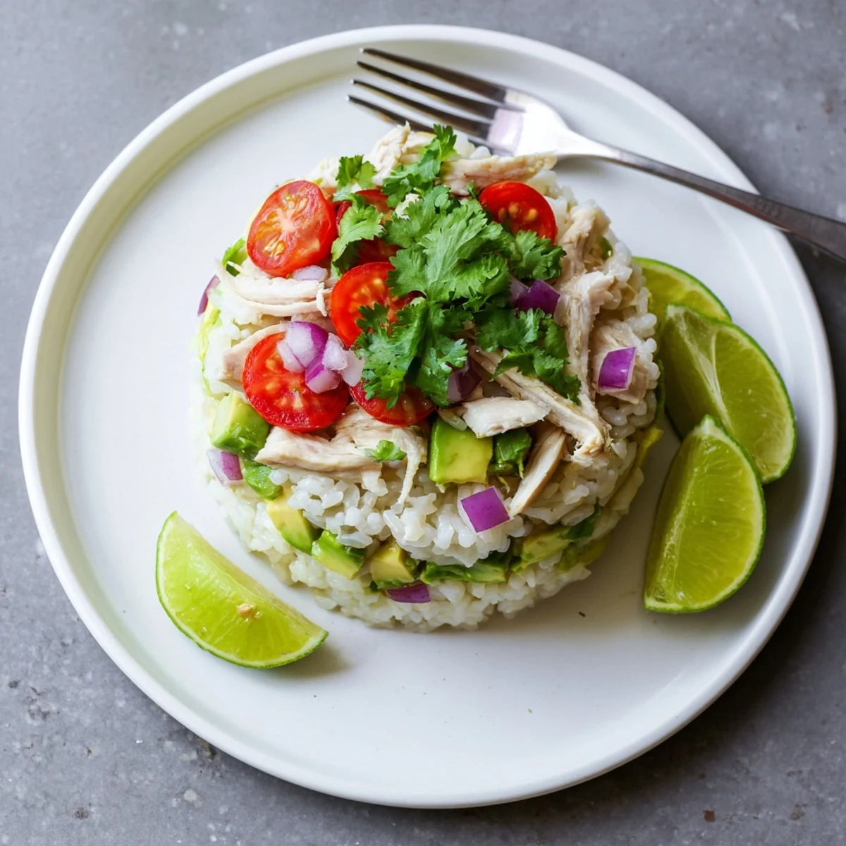 Golden honey lime marinated chicken stacked with fresh avocado and white rice on a white plate