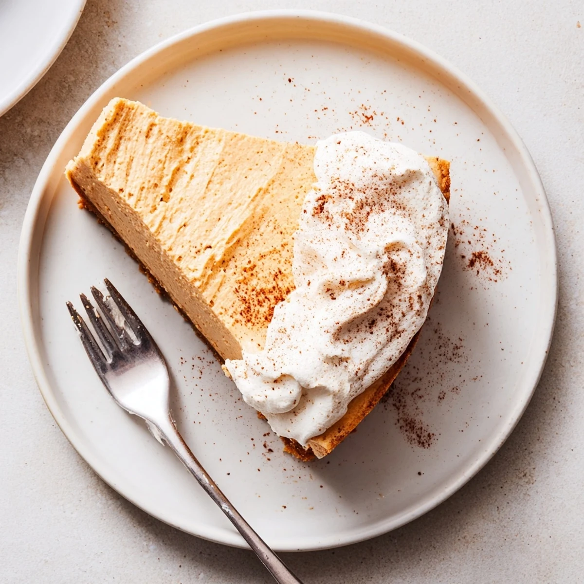 Holiday dessert featuring rich pumpkin spice cheesecake on graham cracker crust topped with fluffy whipped cream