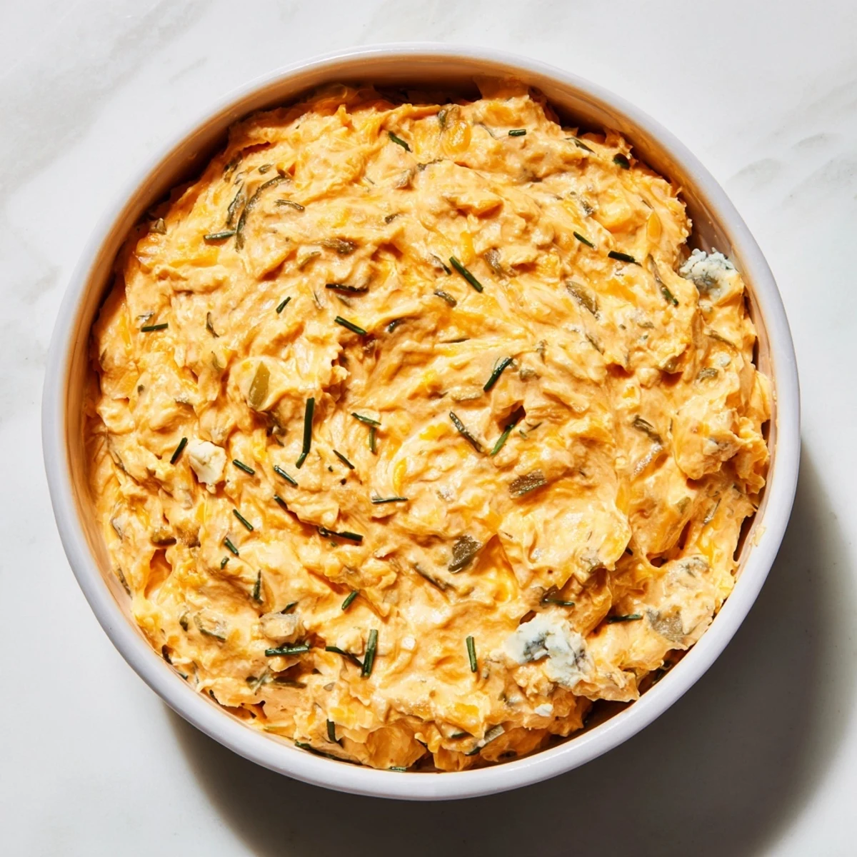 Tangy buffalo pickle dip topped with fresh chives and sliced pickles in rustic bowl