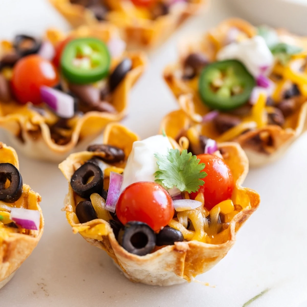 Golden cheesy nacho cups topped with beans, tomatoes, and melted cheese in crispy shells