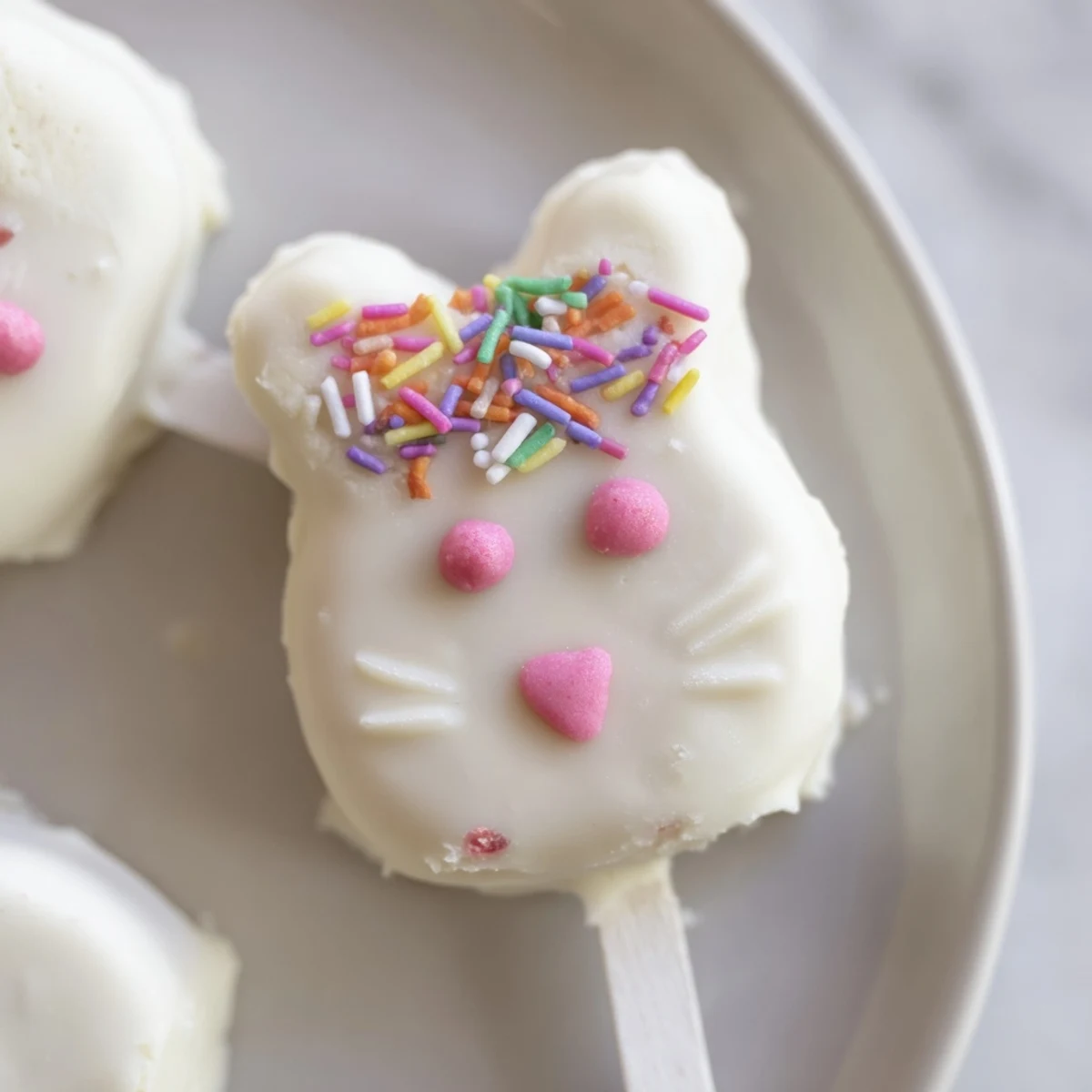 Creamy white chocolate bunny cakesicles decorated with sprinkles for festive Easter treats