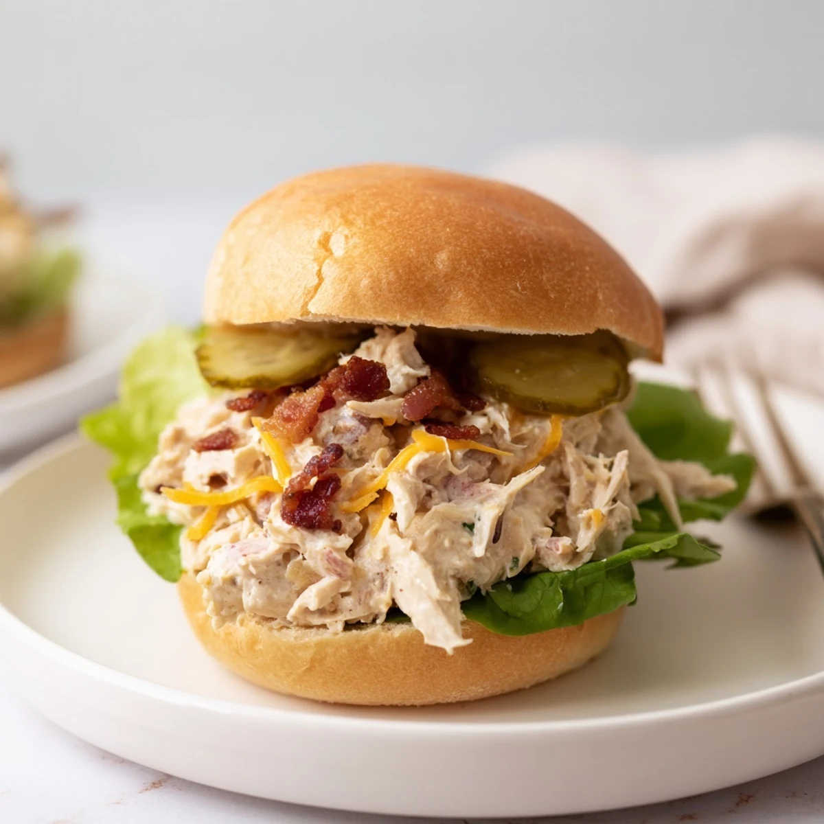 Close-up of Crack Chicken Sandwiches topped with crumbled bacon, pickles, steam rising