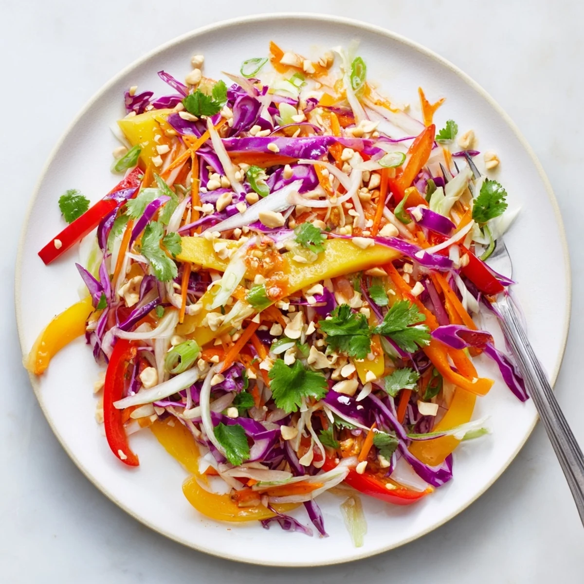 GoldenRefreshing mango slaw with crisp red cabbage and carrots in a white bowl topped with sesame seeds