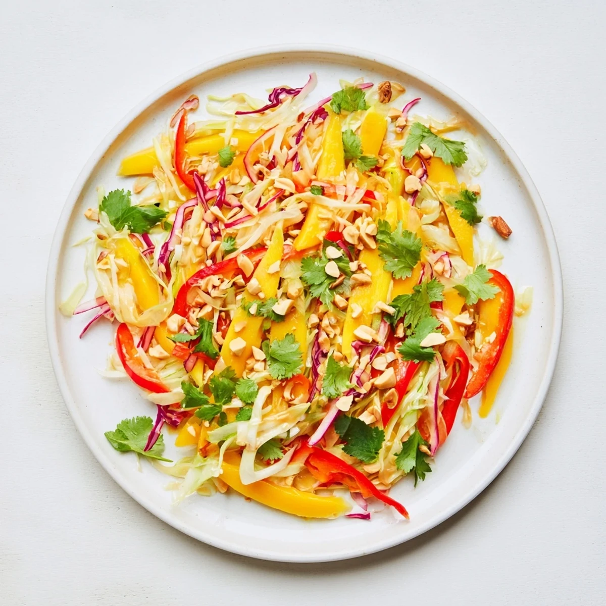 Colorful summer mango slaw with red bell pepper and scallions garnished with roasted peanuts and toasted sesame