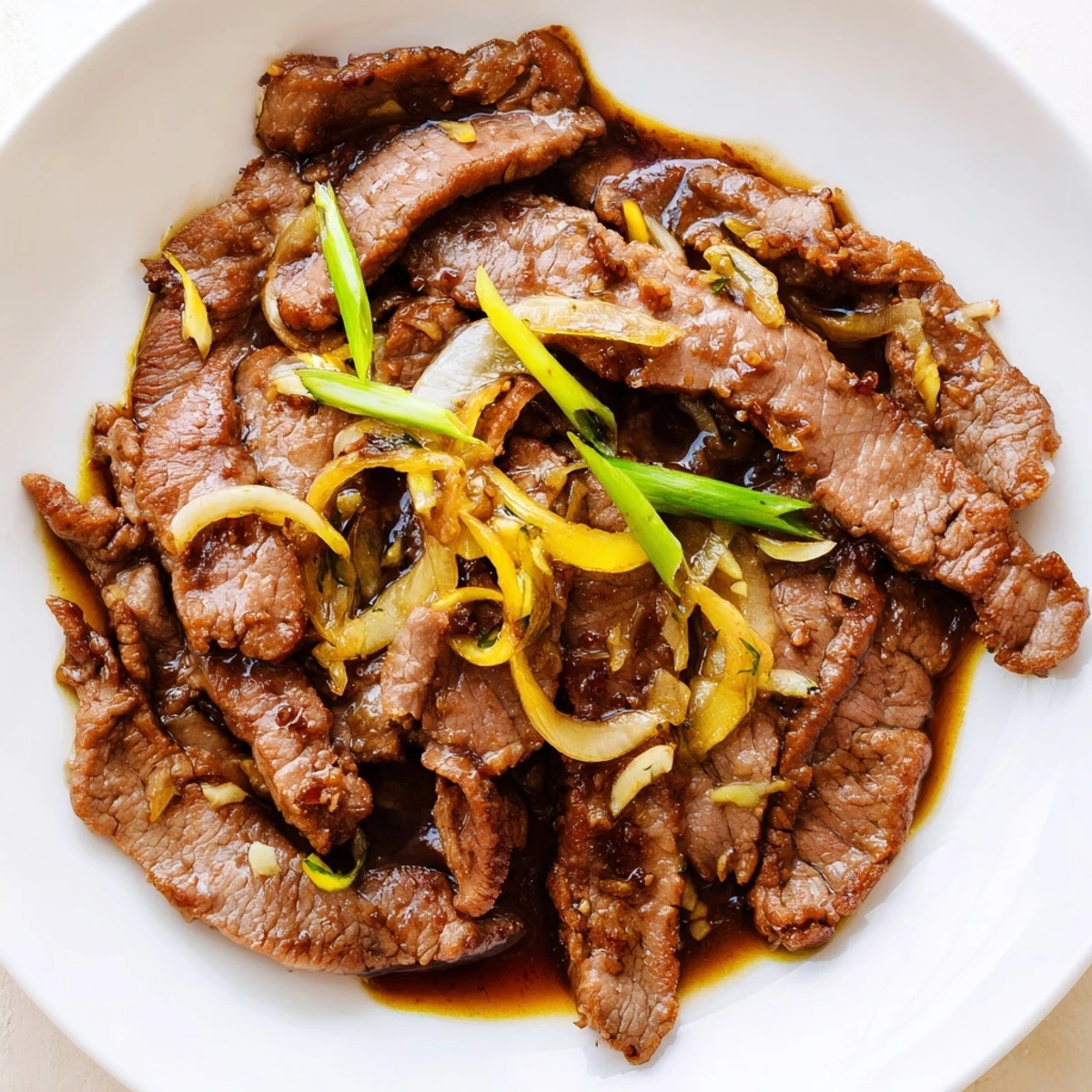 Golden crispy beef and caramelized onion stir fry plated over white rice