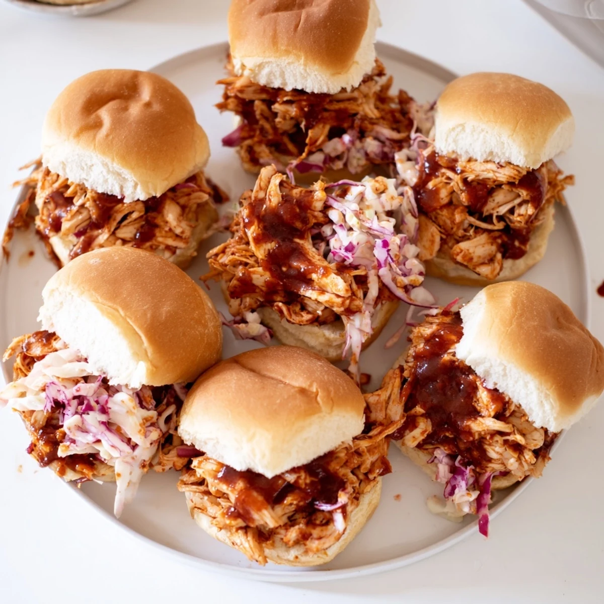 Golden BBQ pulled chicken sliders stacked high on sweet Hawaiian rolls with creamy coleslaw