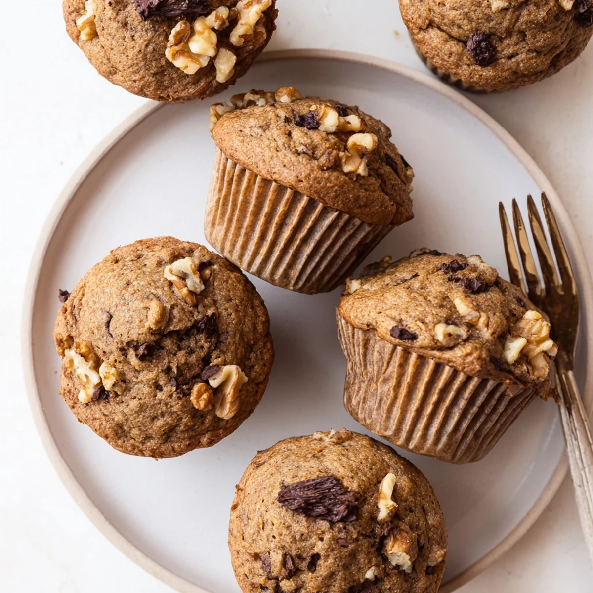 Moist healthy banana nut muffins served on a wooden board with scattered walnut pieces