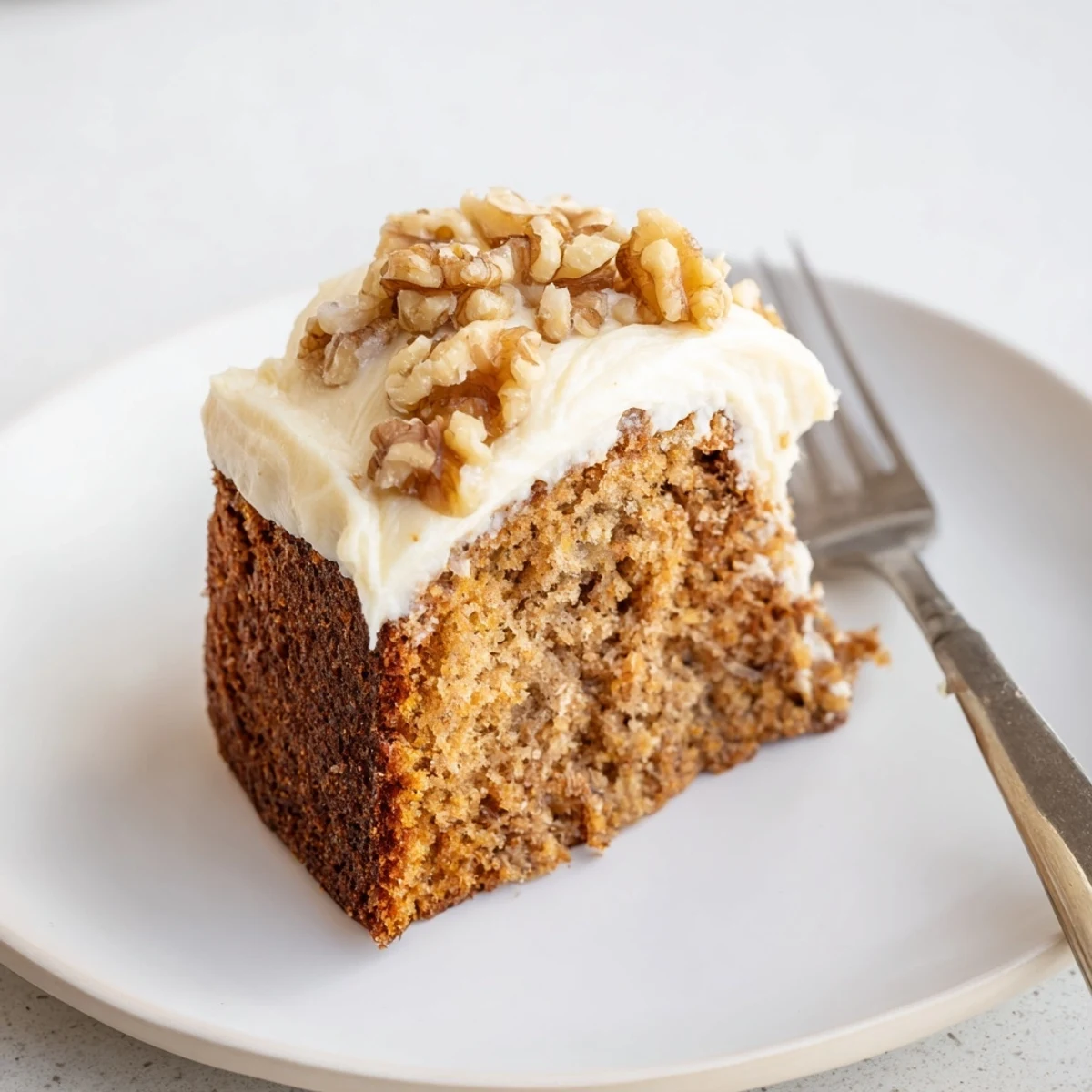Warm slice of Moist Banana Cake served with coffee, fork sinking into it