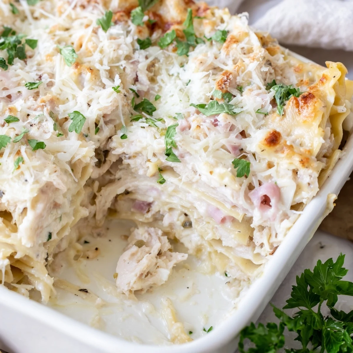 Baked Chicken Cordon Bleu Lasagna dish garnished with fresh parsley and cheesy crust