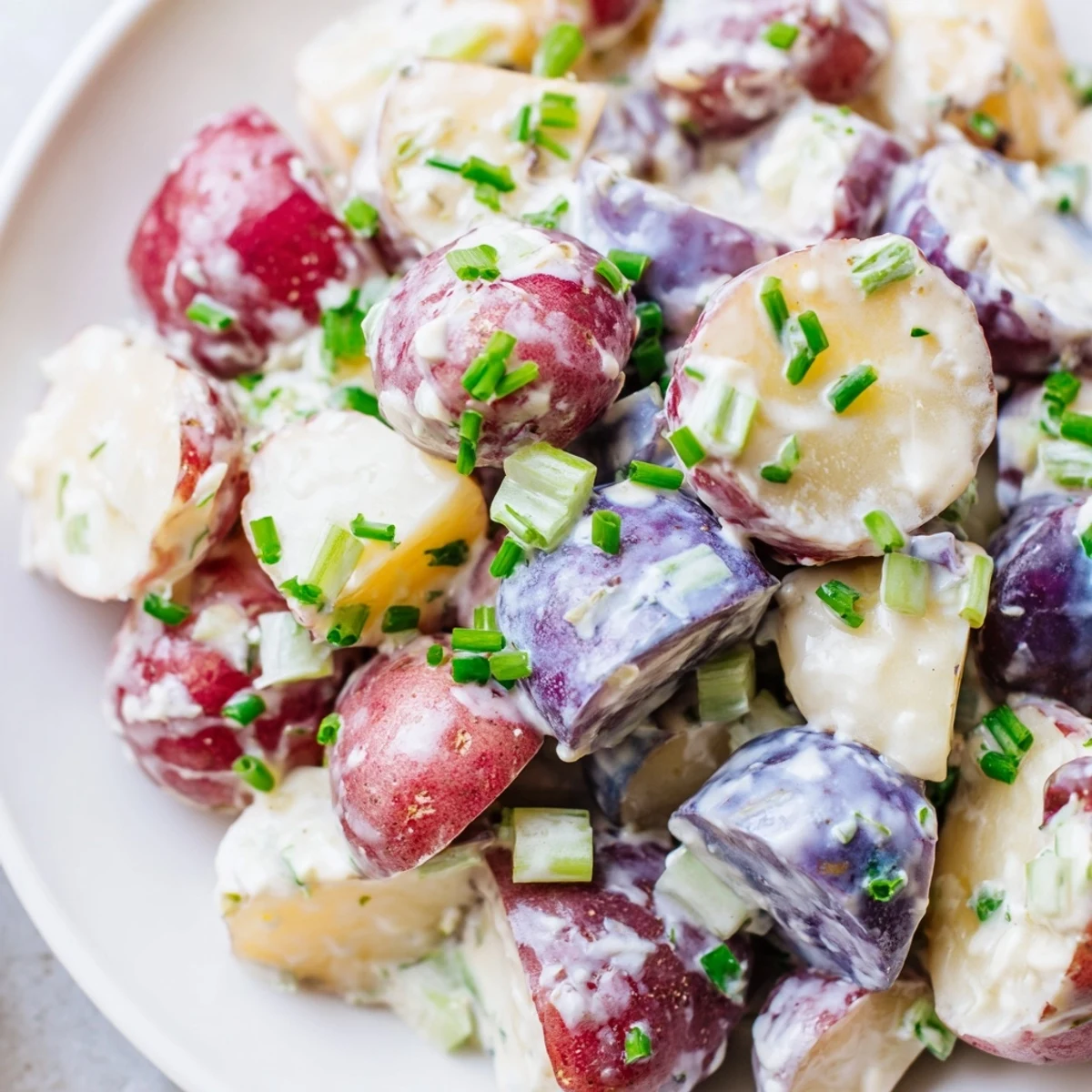 Creamy red white and blue potato salad with crisp celery and tangy mustard dressing piled high