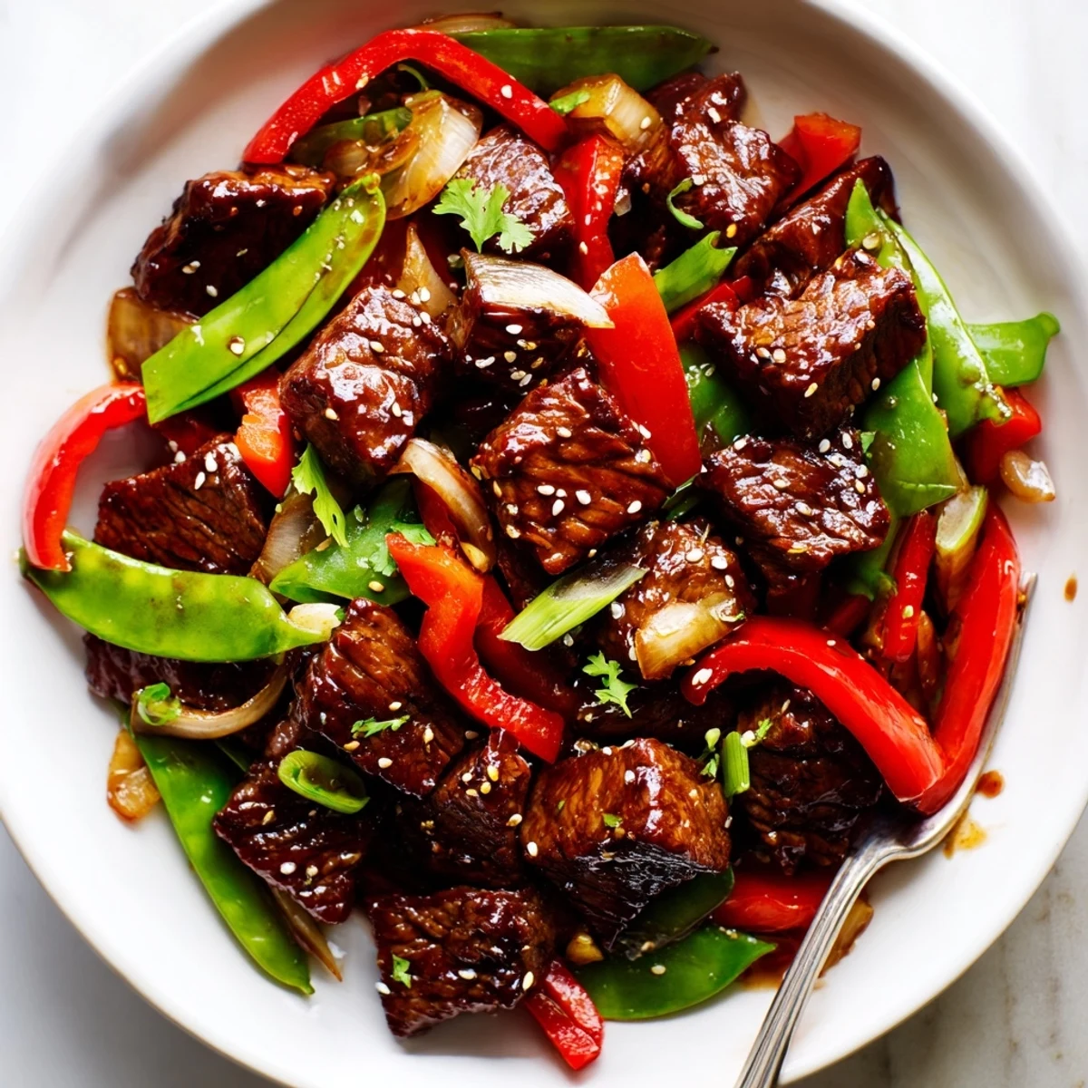 Pan-seared Asian-inspired cube steak sizzling with bell peppers, snap peas, and sesame seeds