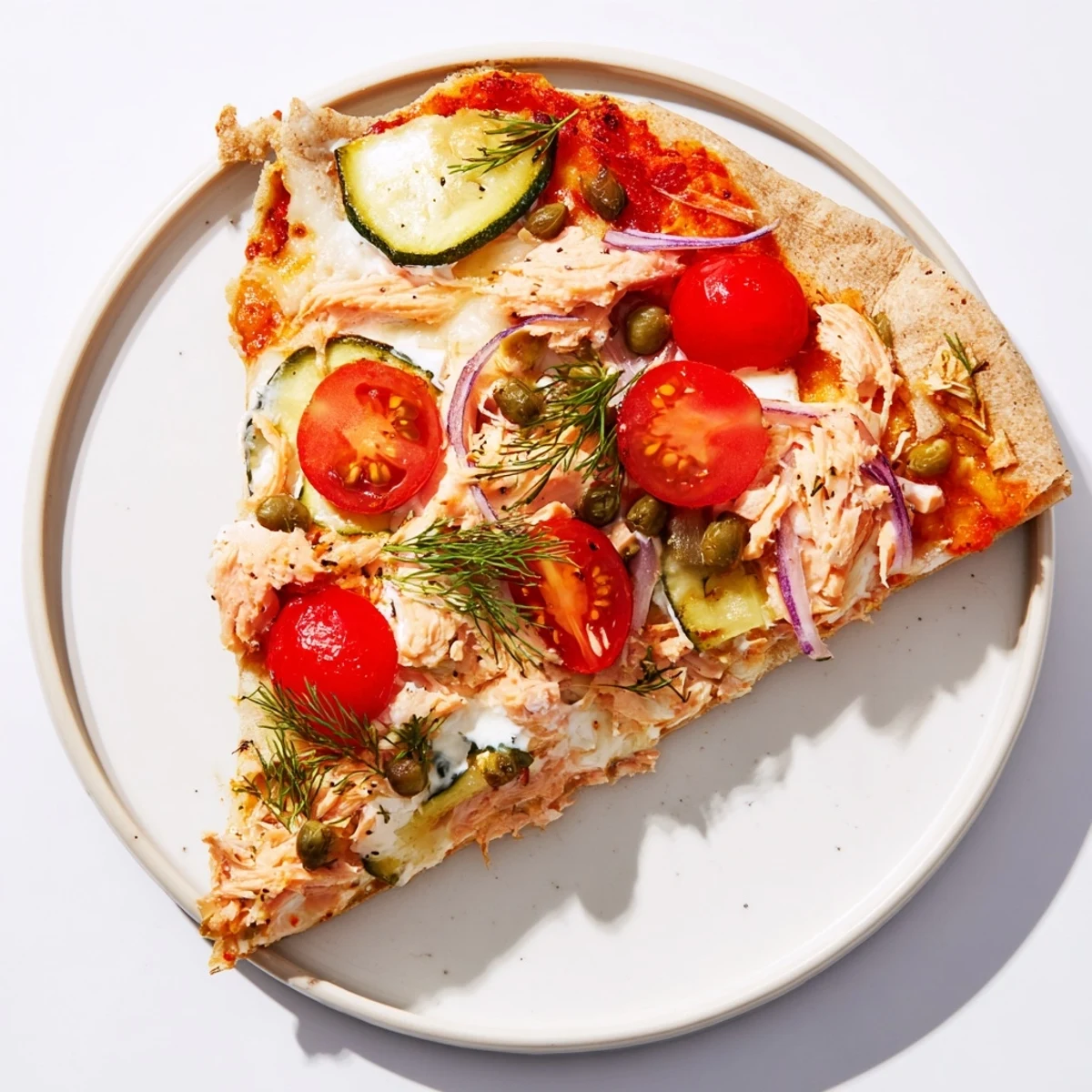Golden tortilla pizza topped with flaked leftover salmon, melted mozzarella, and vibrant fresh vegetables.