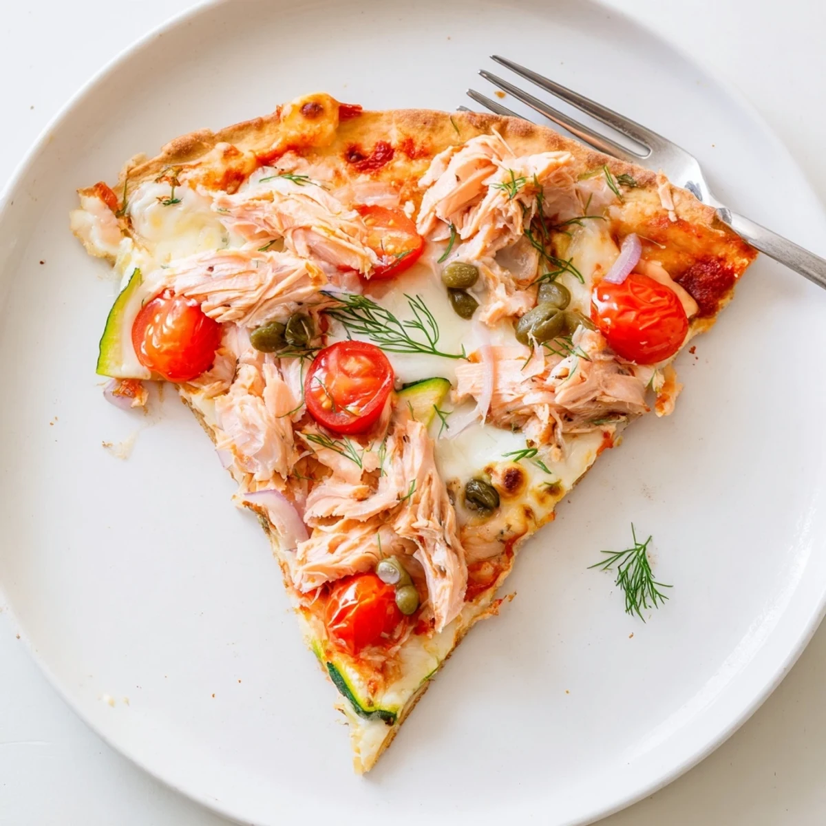 Crispy leftover salmon tortilla pizza baked with bubbling cheese, red onion, and juicy cherry tomatoes.