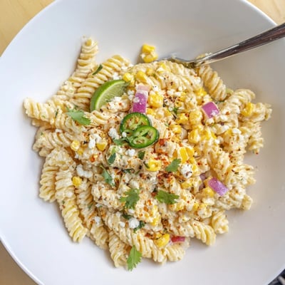 Juicy Street Corn Pasta Salad with creamy cotija, jalapeño bite, lime wedges